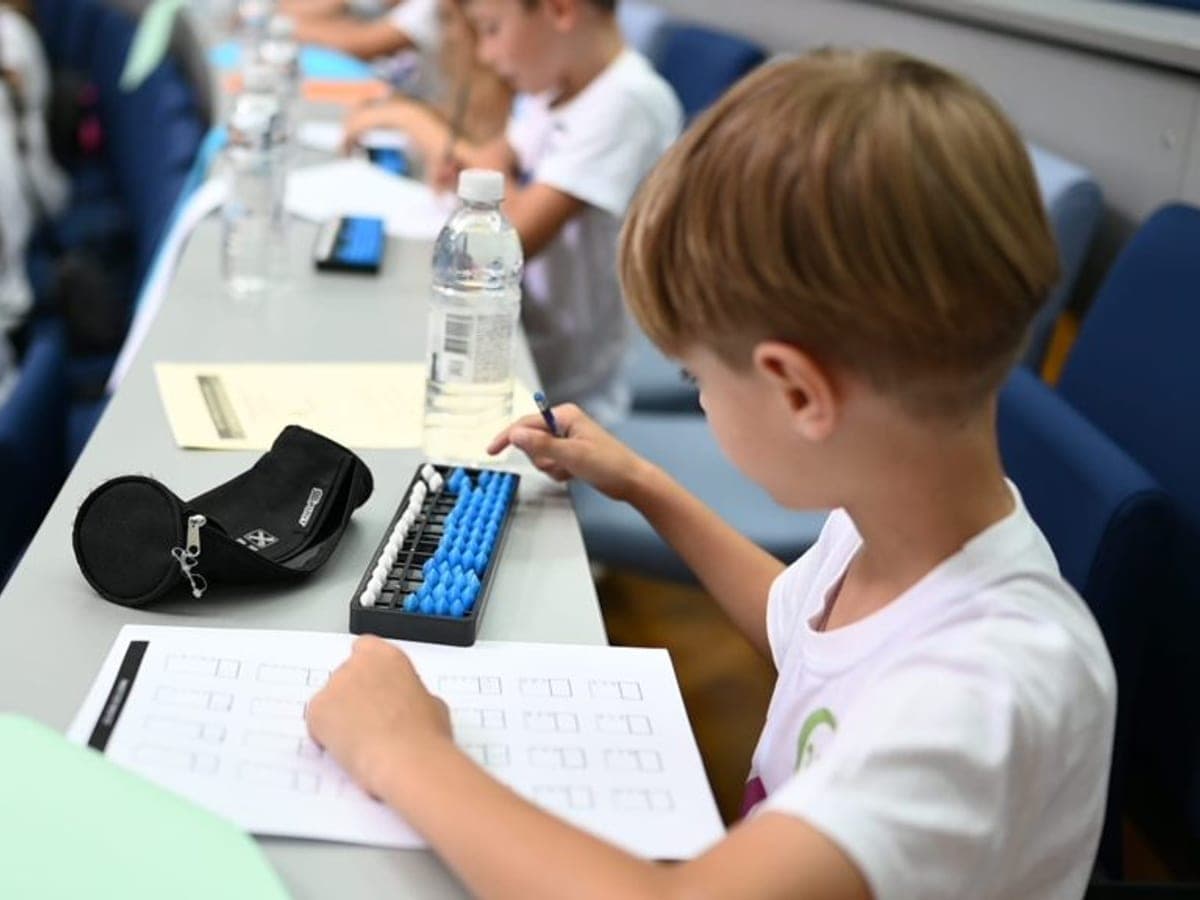 A student calculating on a blue abacus next to a worksheet