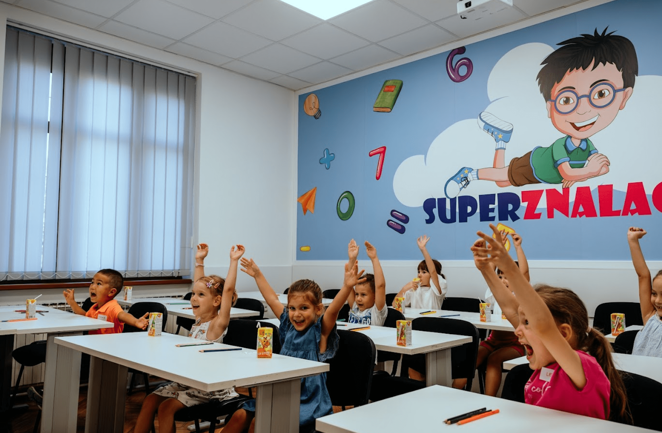 Učenici u razredu šire ruke i vesele se. 